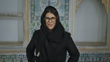 İstanbul 'da süslü bir sehpanın önünde gözlüklü ve siyah atkı takan gülümseyen genç bir İspanyol kadın duruyor..