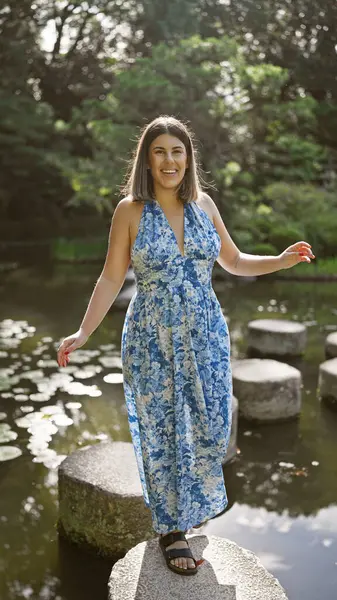 stock image Beautiful hispanic woman's leisurely summer walk along stone path crossing a lake at traditional heian jingu shrine, kyoto