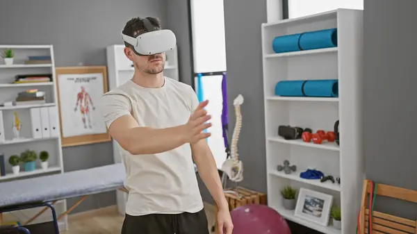 stock image A young hispanic man uses virtual reality in a well-equipped rehabilitation clinic.