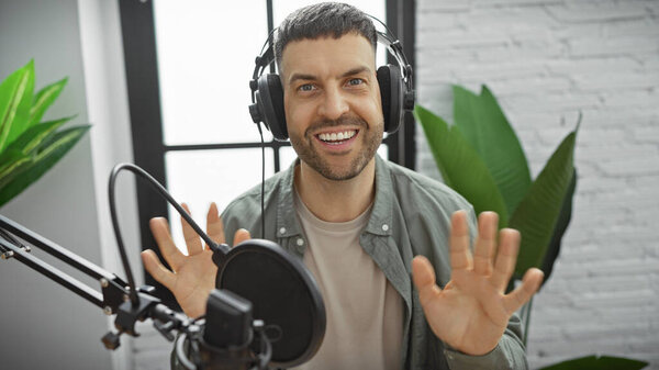 Handsome man with headphones in a radio studio gesturing while recording a podcast