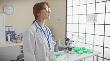 Kendine güvenen genç bir kadın doktor, parlak bir hastane laboratuvarında kollarını kavuşturarak profesyonellik ve uzmanlık gösteriyor..