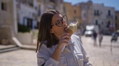 Bari 'nin eski kasabasındaki genç İspanyol kadın güneşli bir günde dondurma külahının tadını çıkarıyor. Puglia, İtalya' nın canlı sokaklarını gösteriyor..