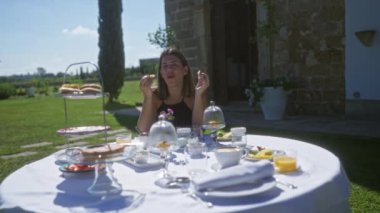 İspanya 'lı genç bir kadın Puglia, İtalya' da bir villada kahvaltıdan keyif alıyor. Çeşitli kahvaltı öğeleri ve Avrupa kırsalının manzaralı bir zemininin yer aldığı güzel bir masa..