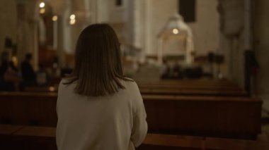 İtalya 'da tarihi bir Hıristiyan kilisesinde dua eden genç bir kadın. Arka planda güzel bir mimari ve dingin bir ortam var..