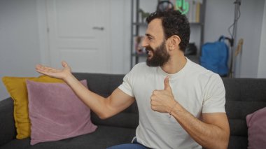 Gündelik giysiler içinde sakallı bir adam modern bir oturma odasında onay veriyor..
