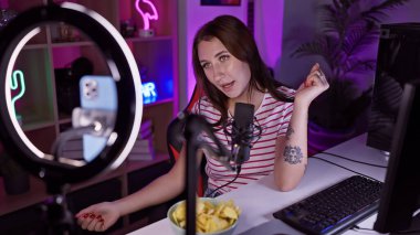 Genç bir kadın geceleri neon ışıklı oyun odasına akarsu gibi akıyor, teknoloji ve yaşam tarzını sergiliyor..