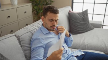 Yakışıklı, sakallı, modern bir oturma odasında belgeyle serinleyen bir İspanyol..