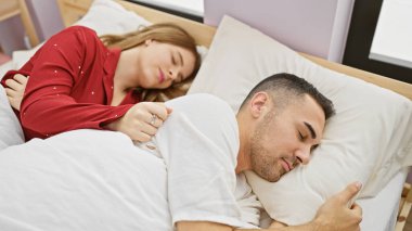 Bir çift, rahat bir yatak odasında huzur içinde uyur. Sevgiyi, birlikteliği ve evin rahatlığını somutlaştırır..