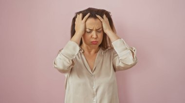 Stresli, başı ağrıyan genç bir İspanyol kadın, pembe bir duvara yaslanmış, ipek bir bluz içindeki rahatsızlığını dile getiriyor..