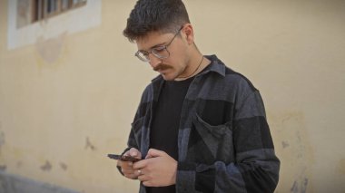 Bıyıklı İspanyol adam. Şehir caddesinde akıllı telefon kullanıyor.