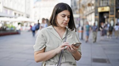 Genç ve güzel İspanyol kadın Viyana sokaklarında akıllı telefon kullanıyor.