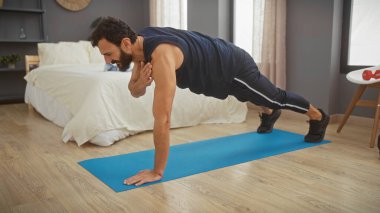 Orta yaşlı bir adam düzenli bir yatak odasında şınav çekerek egzersiz yapıyor. Sağlıklı bir yaşam tarzı sergiliyor..