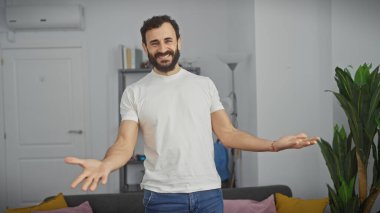 Gülümseyen sakallı adam modern oturma odasında duruyor.