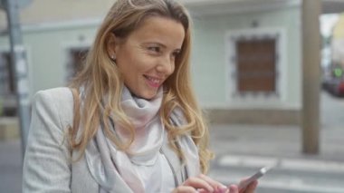 Caddede akıllı telefon kullanan gülümseyen kadın.
