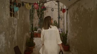 Genç bir İspanyol kadın polignano 'nun tuhaf, süslü sokaklarında geziniyor. Puglia, İtalya' da bir kısrak. Etrafı kaktüs ve canlı asma süsleriyle çevrili..