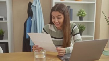 Neşeli, genç bir İspanyol kadın evde dizüstü bilgisayarı açık bir mektup okuyor. Başarı ve memnuniyet hissi yayıyor..