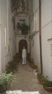 Genç bir İspanyol kadın Puglia, İtalya 'nın büyüleyici, beyaz taş caddelerinde geziyor. Etrafı canlı saksı bitkileriyle ve tarihi mimariyle çevrili..