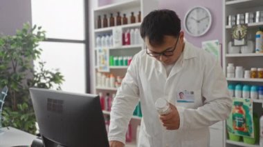 Beyaz önlüklü genç bir eczacı, içi ürünlerle dolu bir eczane odasında şişeyi incelerken, kapalı bir perakende ortamında detaylara dikkat edilmesi gerektiğini vurguluyor..