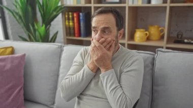 Şok olmuş orta yaşlı bir adam evde gizli bir hata yüzünden elleri şokla ağzını kapatıyor.