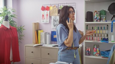 Renkli bir terzi dükkanında İspanyol kadın telefonda konuşuyor kumaş, desenler ve mankenlerle.