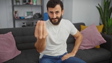 Sakallı adam el kol hareketleri yapıyor modern oturma odası kanepesi günlük kıyafetler.