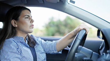 Genç, güzel, İspanyol bir kadın yolda araba kullanıyor.