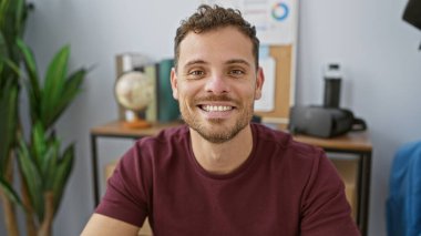 Ofiste sakallı, gülümseyen İspanyol bir adam, yaklaşımı ve profesyonelliği tasvir ediyor..