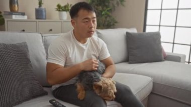 Oturma odasında bir köpekle kanepede otururken yüzünü şoka sokan genç adam..