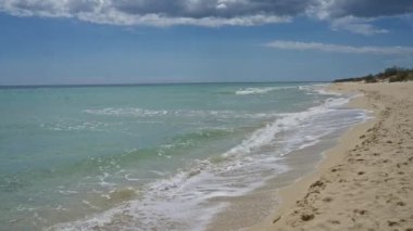 Salento, puglia, İtalya 'daki dingin pescoluse plajı turkuaz sular, kumlu kıyılar ve kabarık bulutlu açık mavi bir gökyüzü..
