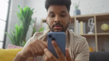 Yakışıklı Afro-Amerikalı adam evde akıllı telefon kullanıyor, rahat, modern, teknoloji, apartman, iç mekan, yetişkin, erkek, insan.