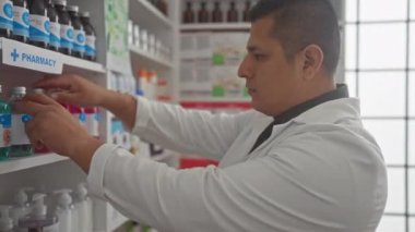 İspanyol bir eczacı, çağdaş bir eczanede kapalı bir rafta ilaç şişeleri düzenliyor..