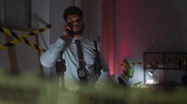 Polis dedektifi rolündeki Afrikalı Amerikalı bir adam kapalı bir suç mahallinde telefon görüşmesi yapıyor..