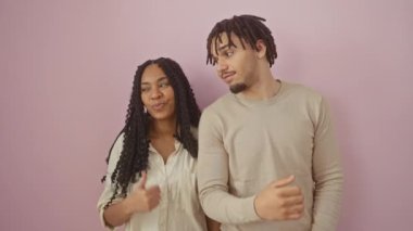 Neşeli, güzel bir çift yan yana duruyor, başparmaklarını gösteriyorlar, yüzlerinde ışıl ışıl gülücükler. Pembe izole bir duvarın üzerinde, sevginin ve pozitifliğin neşe dolu bir ifadesi.