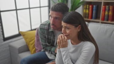 İspanyol çift evlerinde oturma odasındaki koltukta rahat ve endişeli bir şekilde oturuyorlar.