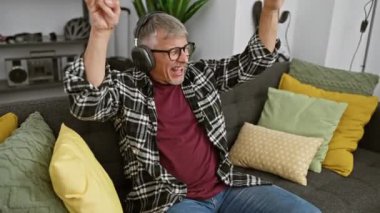 Kapalı koltukta kutlama yapan kulaklıklı mutlu son sınıf öğrencisi.