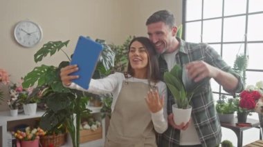 Çiçekçi erkek ve kadın çiçekçiler çiçekçi dükkanının içinde hapla selfie çekiyorlar..