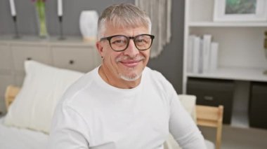 Neşeli orta yaşlı adam yatak odasında diş sağlığını gösteriyor.