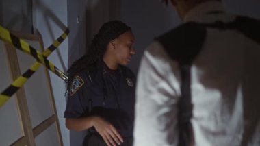 Afro-Amerikalı bir kadın polis. İçerideki bir suç mahallini güvenlik bandıyla araştırıyor. Ve erkek arkadaşının dikkati dağınık..