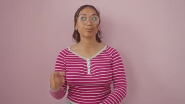 Çizgili tişörtlü, pembe izole edilmiş arka planda duran heyecanlı genç İspanyol kadın. Gülümsüyor, akıllı 'aha' ile işaret ediyor! Başarı anı.