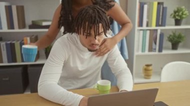 Sevecen kadın, odaklanmış erkeği kucaklıyor evde dizüstü bilgisayarla çalışıyor, sevgi ve destek gösteriyor..