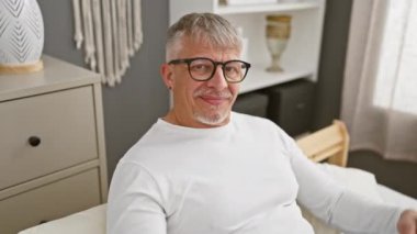 Neşeli orta yaşlı bir adam, saçları gri, pijamalarıyla başını işaret ediyor, kapalı bir fikir cenneti. Hatırladın mı? Odasındaki yatakta yavaşça gülümsüyor, harika bir hafızası var.!