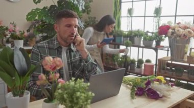 Çiçekçi dükkanında çalışan bir adam ve bir kadın çeşitli bitki ve çiçeklerle dolu bir adam ve dizüstü bilgisayar kullanan bir adam..
