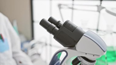 Laboratuvar ortamında mikroskop kullanan odaklanmış bir Afrikalı kadın bilim adamı.