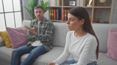 Kadın ve erkek kanepede tartışıyorlar, rahat bir oturma odasında stres ve rahatlık gösteriyorlar..