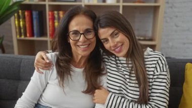 Neşeli bir anne ve kız, sıcak bir oturma odasında kucaklaşıp, aile sevgisini ve mutluluğunu gösteriyorlar..