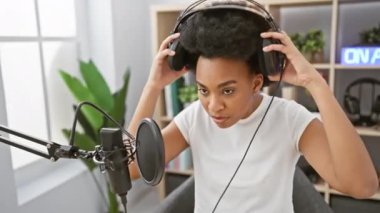 Radyo stüdyosunda kulaklık takan Afrikalı Amerikalı bir kadın.