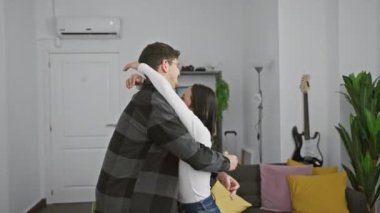 Sevgi dolu bir çift, sıcak bir oturma odasında kucaklaşır. Modern bir evin içinde sevgi ve mutluluk taşırlar..