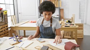 Çalışkan bir siyahi kadın, iyi donanımlı marangozluk atölyesinde ahşabı titizlikle ölçer, profesyonellik ve adanmışlık hissi yayar..