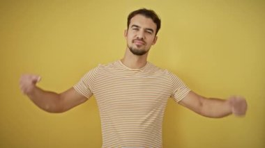 Neşeli, İspanyol asıllı, gururla kendini gösteren, kendini dünyanın tepesinde hisseden genç adam! Çizgili bir tişört giyiyor, izole edilmiş sarı bir arkaplanda duruyor, saf bir güven yayıyor..