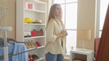 Sarışın kadın kostüm odasında hayal kırıklığına uğramış gömleğini çıkarıyor, seçiminden bunalmış hissediyor..